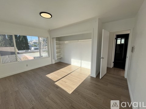 A spacious room with wooden flooring and a large window.