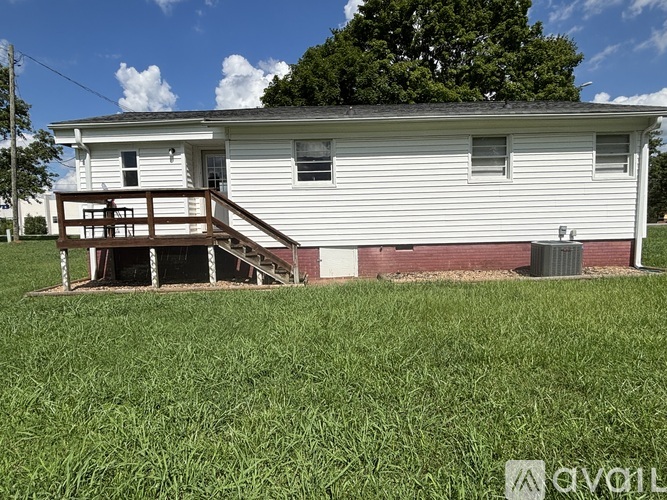 A white house with a red brick base and a wooden deck.