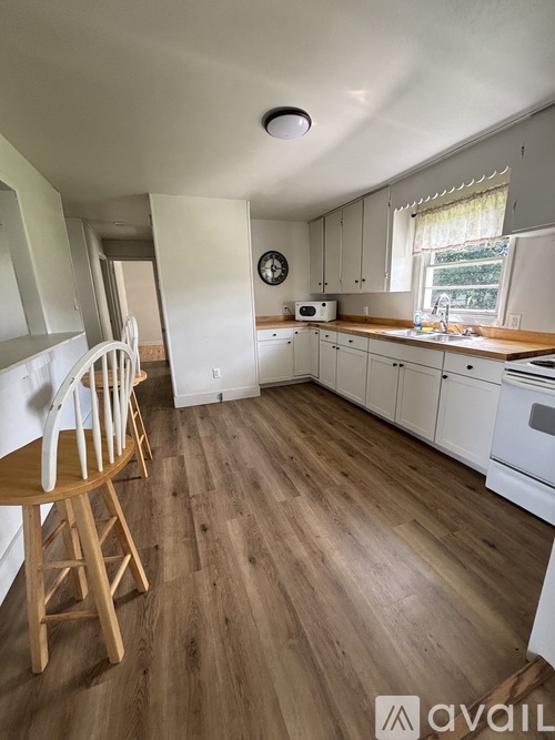 A kitchen with wooden floors and white cabinets.