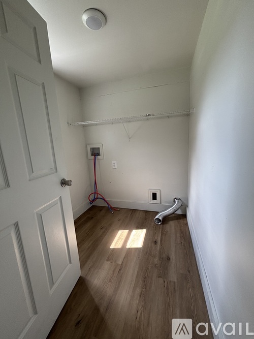 A room with a door, a wall socket, and a pipe on the floor.