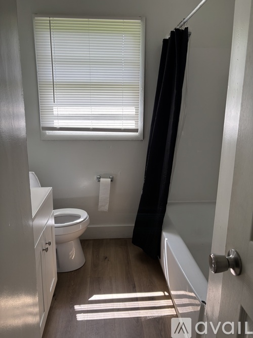 A bathroom with a toilet, a bathtub, and a window with blinds.