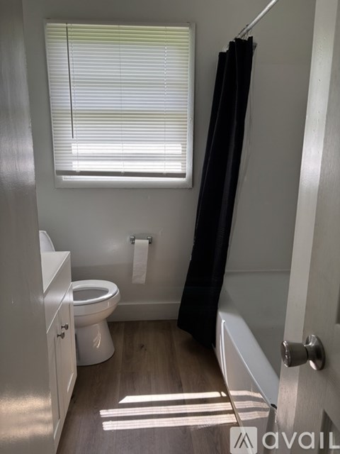 A bathroom with a toilet, a bathtub, and a window with blinds.