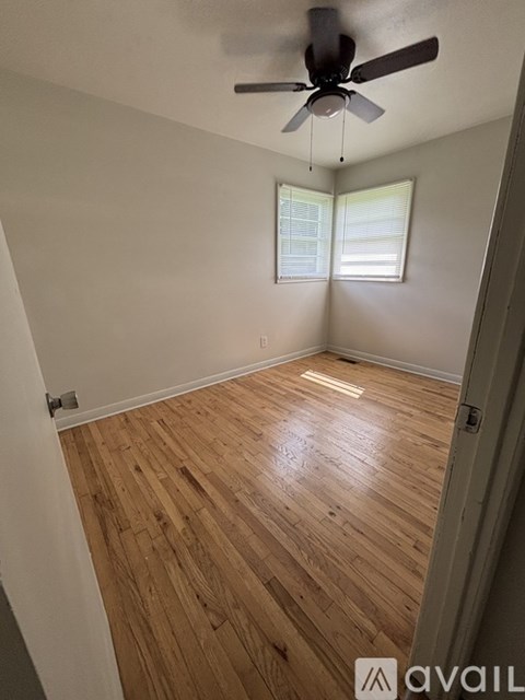A room with a ceiling fan and wooden flooring.