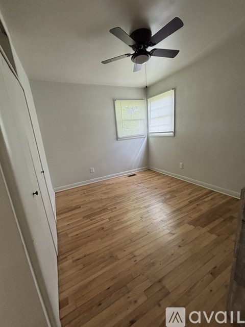 A room with a ceiling fan and wooden flooring.