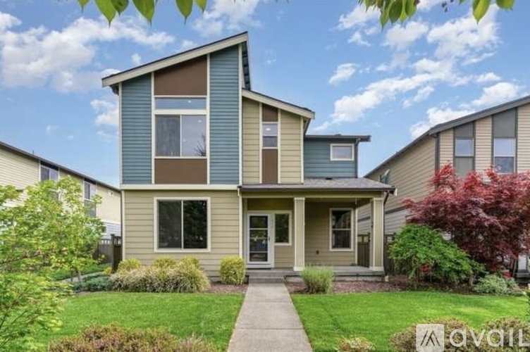 A two-story house with a front porch and a well-maintained lawn.
