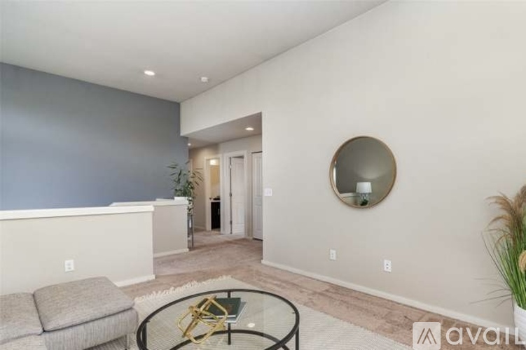 A living room with a grey couch and a glass table.