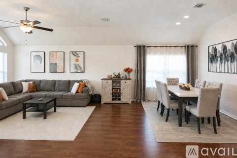 A living room with a grey sofa, a coffee table, a dining table with chairs, and a ceiling fan.