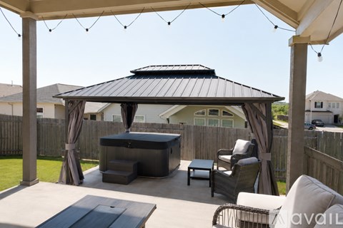 A patio with a gazebo, chairs, and a table.