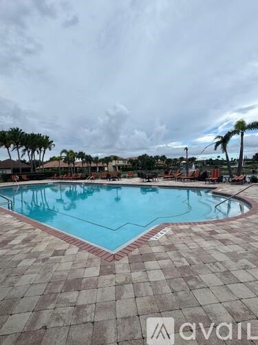 A large swimming pool surrounded by a brick patio.