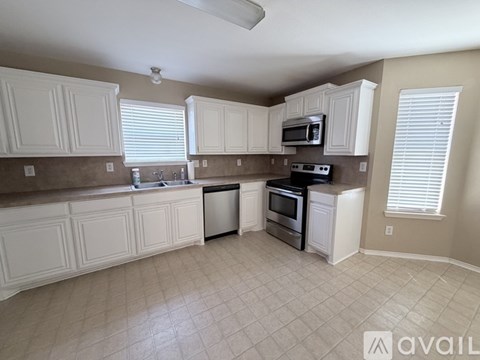 A kitchen with white cabinets and brown countertops.