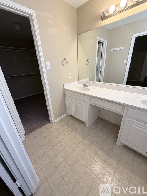 A bathroom with a white sink vanity and a mirror above it.