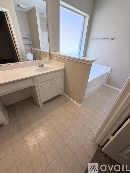 A bathroom with a sink, mirror, and a window.