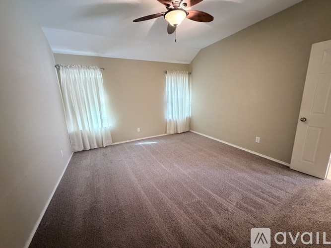 A room with a carpeted floor and a ceiling fan.