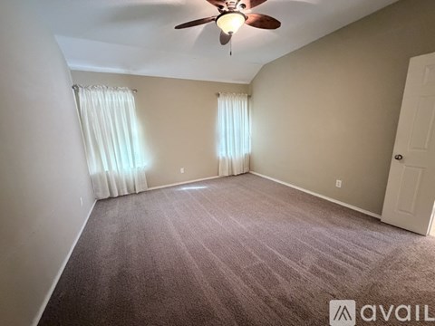 A room with a carpeted floor and a ceiling fan.