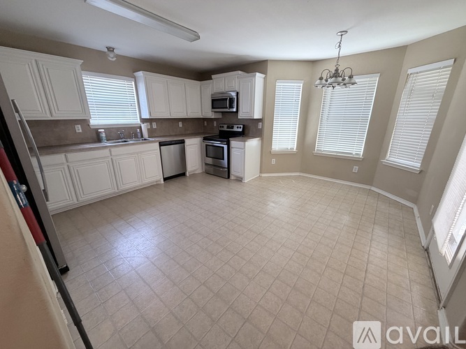 A kitchen with white cabinets and a tile floor.