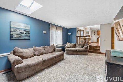 A living room with a couch, a chair, and a painting on the wall.