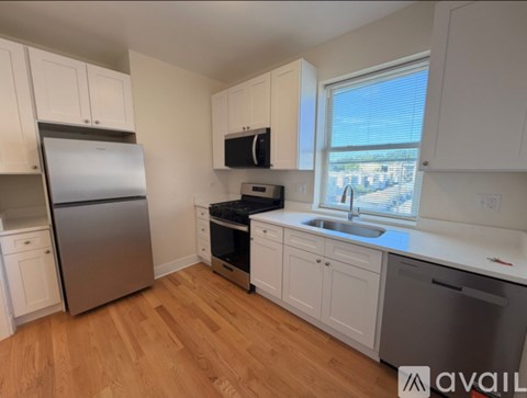 A kitchen with white cabinets and a wooden floor.