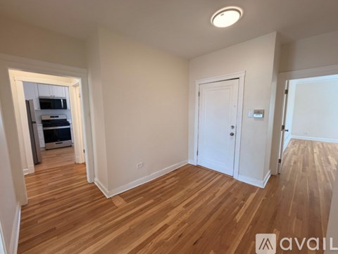 A room with wooden floors and white walls, with a door on the right side.