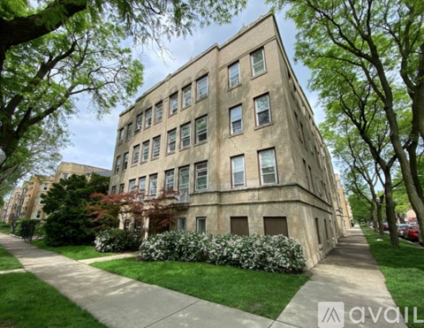 A tall building with many windows is surrounded by trees and bushes.