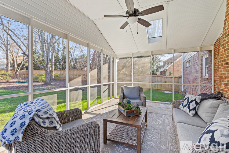 A sunny patio with a wicker couch and a ceiling fan.