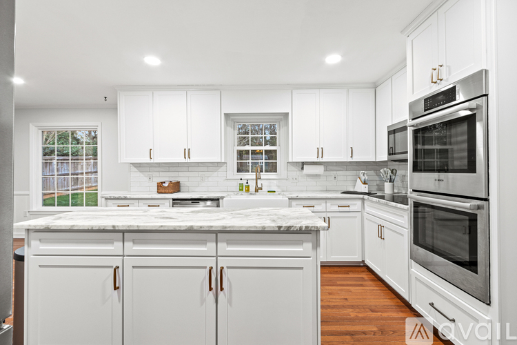 A modern kitchen with white cabinets and stainless steel appliances.