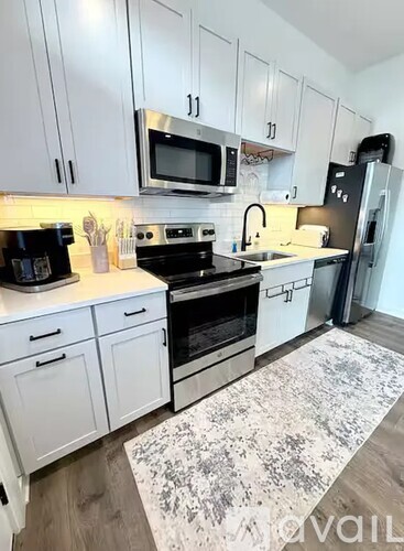 A kitchen with white cabinets and a black fridge.