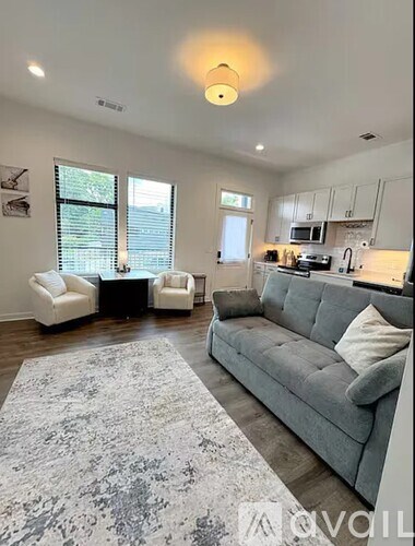 A living room with a grey couch and a rug.