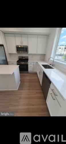 A kitchen with white cabinets and a wooden floor.
