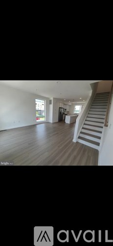 A spacious room with wooden flooring and a staircase leading to another level.