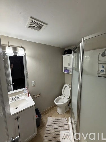A bathroom with a toilet, sink, and mirror.