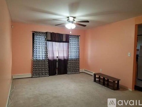 A room with orange walls, a ceiling fan, and a window with curtains.