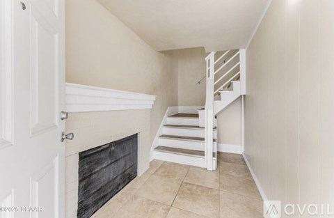 A white door is on the left of a fireplace with a black mantle.