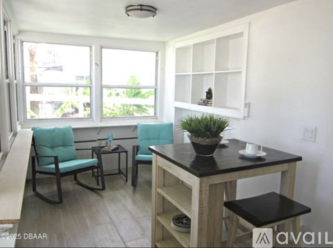 A small table with a potted plant on it and two chairs.