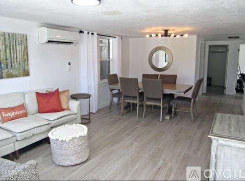 A living room with a white couch, a round mirror, and a painting on the wall.