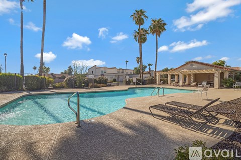 A pool surrounded by palm trees and a house in the background.