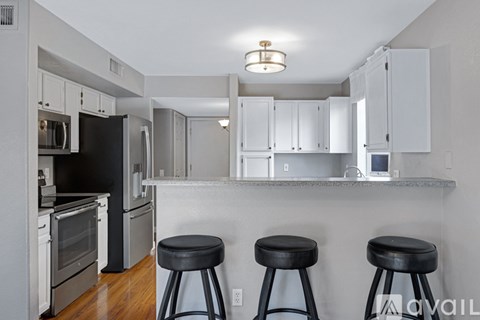 A kitchen with white cabinets and black appliances.