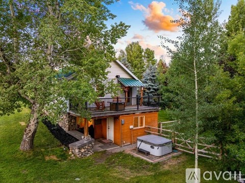 A house with a deck and a hot tub surrounded by trees.