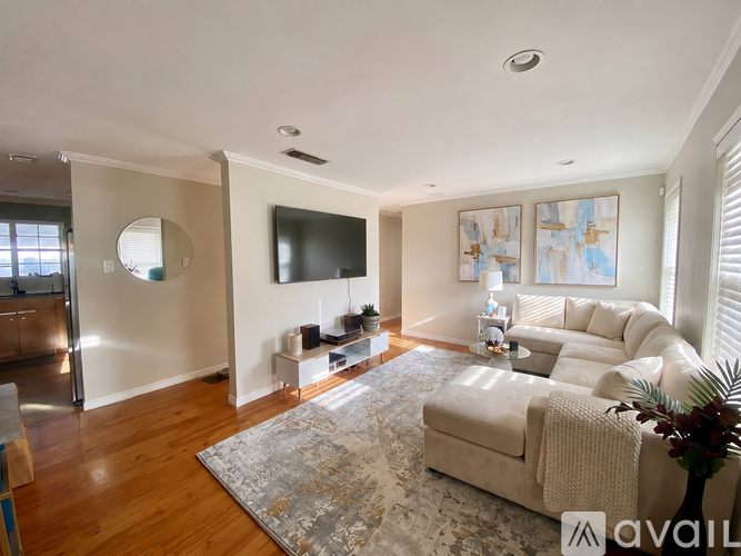 A living room with a couch, a rug, a television, and a painting on the wall.