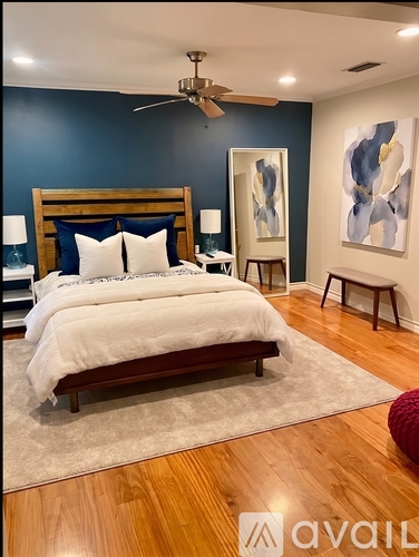 A bedroom with a large bed and a ceiling fan.