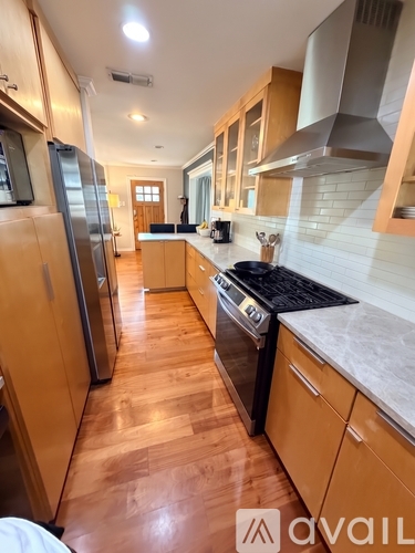 A kitchen with wooden floors and a refrigerator on the left.