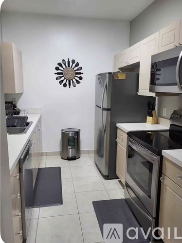 A kitchen with a black refrigerator and a white wall with a sun design.
