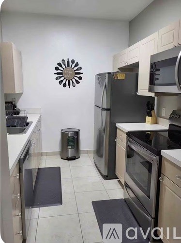 A kitchen with a black refrigerator and a white wall with a sun design.