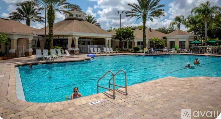 A large outdoor swimming pool with people in it and a building in the background.