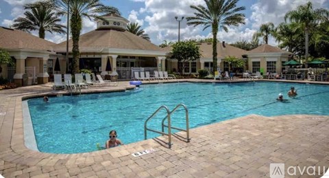 A large outdoor swimming pool with people in it and a building in the background.