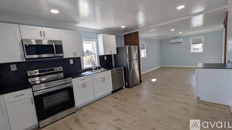 A kitchen with white cabinets and black countertops.