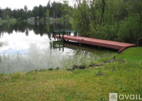 A dock extends into a lake with a grassy shore.