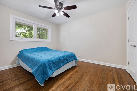 A bedroom with a bed covered in a blue comforter and a ceiling fan.