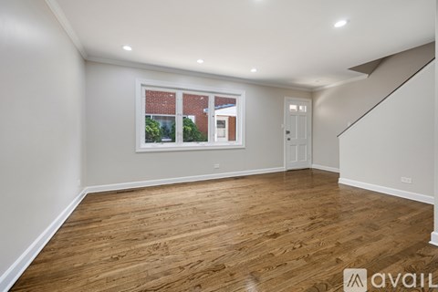 A spacious room with wooden flooring and a window showing a view of a building outside.