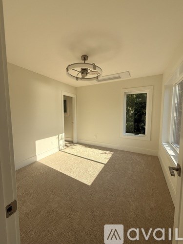 A room with a carpeted floor and a ceiling fan.