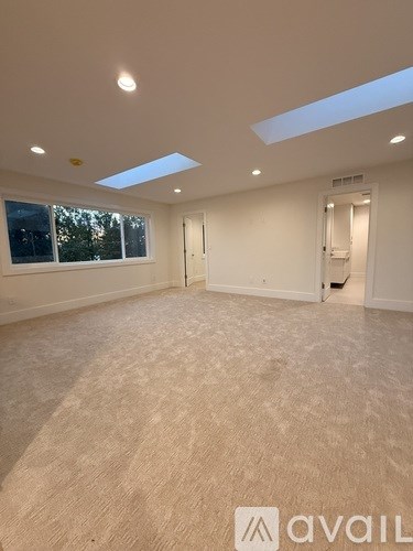 A spacious room with a skylight and carpeted floor.